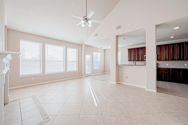 unfurnished living room featuring ceiling fan, light tile patterned floors, a healthy amount of sunlight, and high vaulted ceiling