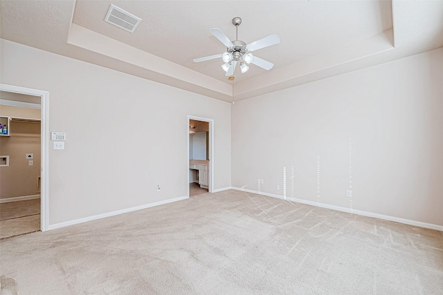 carpeted empty room with a tray ceiling and ceiling fan