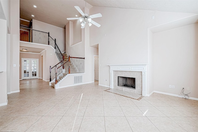 unfurnished living room with a tiled fireplace, ceiling fan, high vaulted ceiling, and light tile patterned flooring