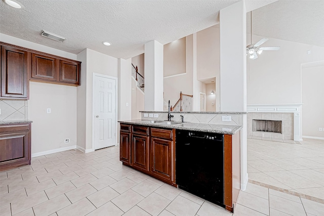 kitchen with sink, light stone countertops, a fireplace, black dishwasher, and light tile patterned flooring