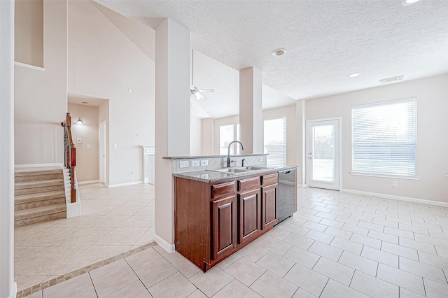 kitchen featuring dishwasher, sink, ceiling fan, light tile patterned flooring, and light stone counters