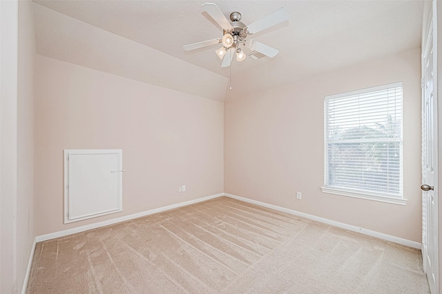 empty room featuring ceiling fan, light colored carpet, and vaulted ceiling