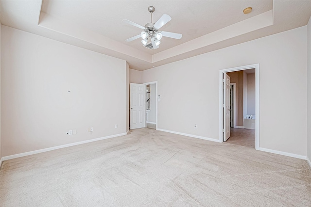 carpeted empty room featuring a raised ceiling and ceiling fan