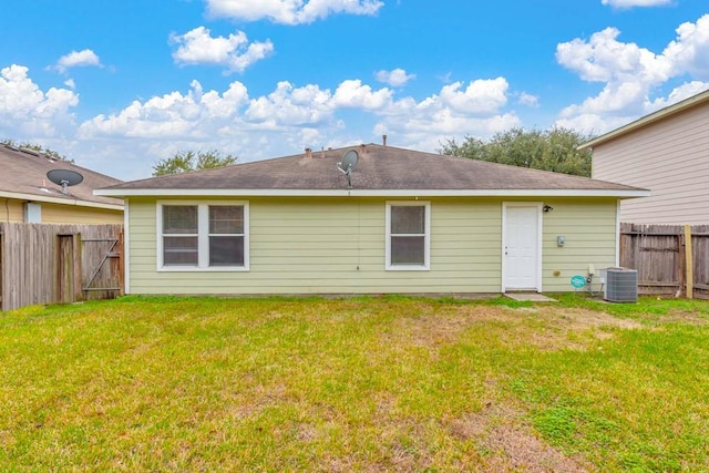 rear view of property featuring a lawn and central air condition unit