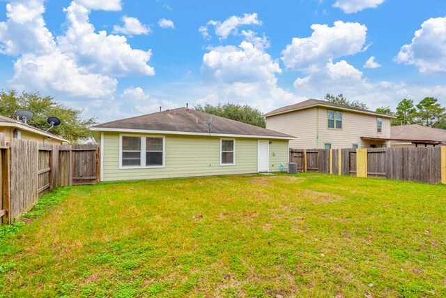 rear view of property featuring cooling unit and a yard