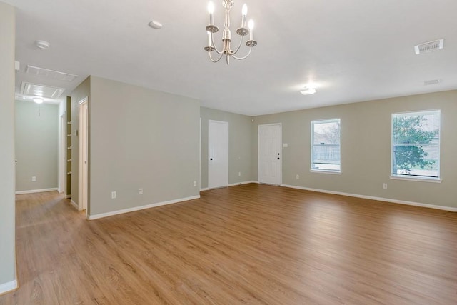 spare room featuring a chandelier and light wood-type flooring