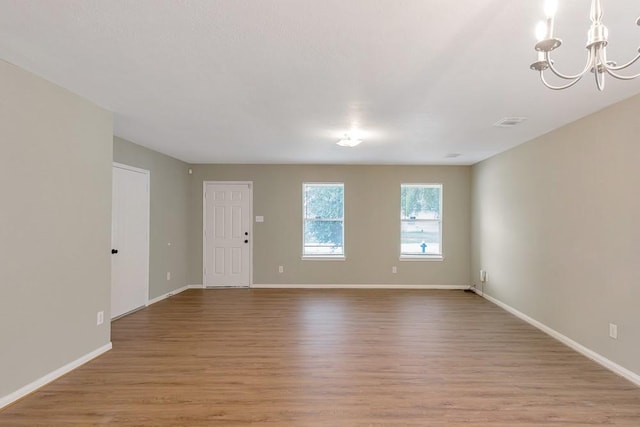 unfurnished room with light hardwood / wood-style floors and a notable chandelier