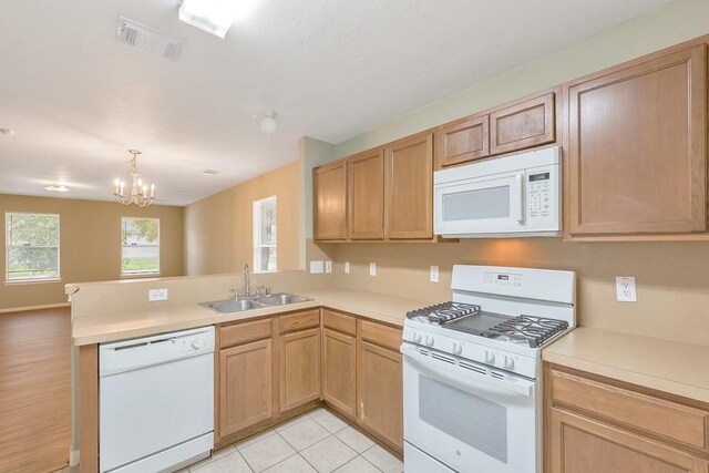 kitchen featuring sink, kitchen peninsula, a chandelier, white appliances, and light tile patterned flooring