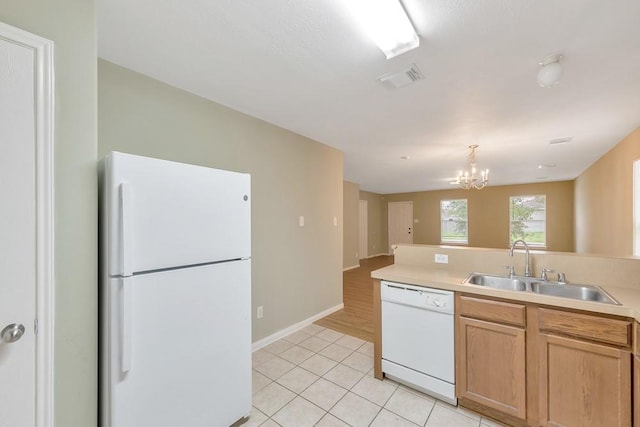 kitchen featuring white appliances, sink, light tile patterned floors, light brown cabinetry, and a notable chandelier