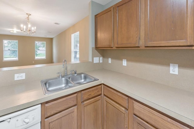 kitchen featuring white dishwasher, hanging light fixtures, a notable chandelier, and sink