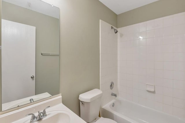 full bathroom featuring vanity, tiled shower / bath combo, and toilet