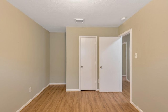 unfurnished bedroom with a textured ceiling and light wood-type flooring