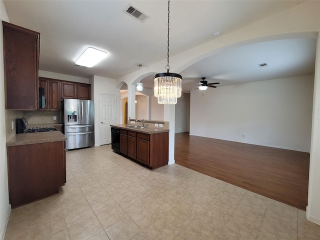 kitchen with stove, sink, stainless steel refrigerator with ice dispenser, hanging light fixtures, and black dishwasher