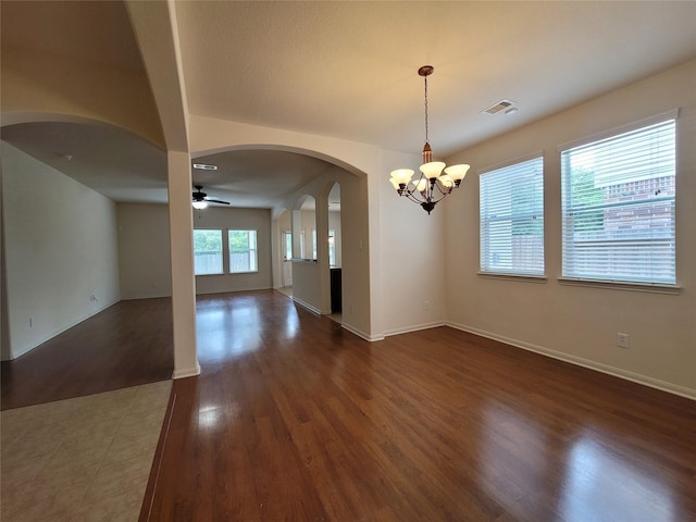 spare room with ceiling fan with notable chandelier and dark wood-type flooring