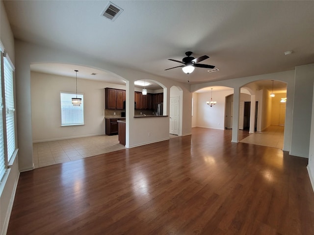 unfurnished living room with ceiling fan with notable chandelier and light tile patterned floors