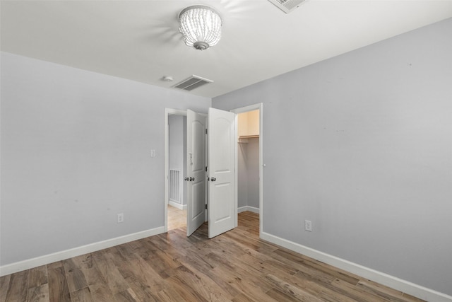 unfurnished bedroom with light wood-type flooring, a spacious closet, and a closet