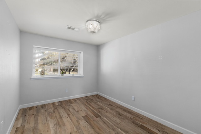 unfurnished room featuring hardwood / wood-style flooring and a chandelier