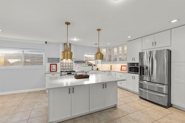 kitchen with stainless steel appliances, a kitchen island, pendant lighting, light tile patterned floors, and white cabinetry