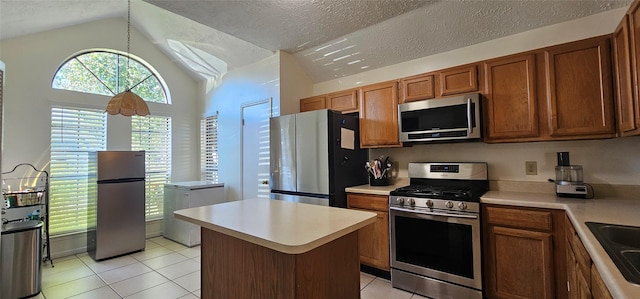 kitchen featuring vaulted ceiling, light tile patterned floors, a textured ceiling, a kitchen island, and stainless steel appliances