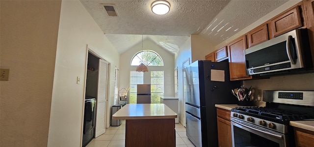 kitchen with lofted ceiling, light tile patterned floors, a textured ceiling, a kitchen island, and stainless steel appliances