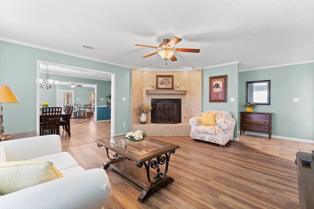 living room with hardwood / wood-style flooring, ceiling fan, crown molding, and a textured ceiling