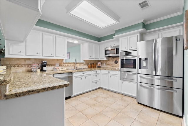 kitchen with sink, stainless steel appliances, light tile patterned floors, tasteful backsplash, and white cabinets