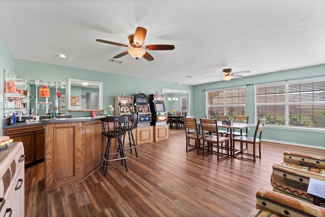 kitchen featuring a kitchen bar, a textured ceiling, dark hardwood / wood-style flooring, and ceiling fan