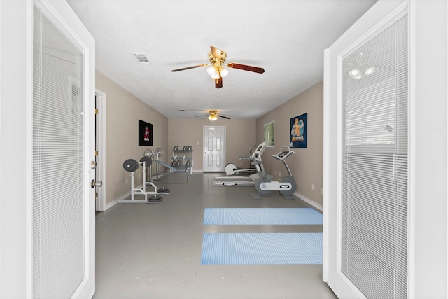 exercise area with ceiling fan and a textured ceiling