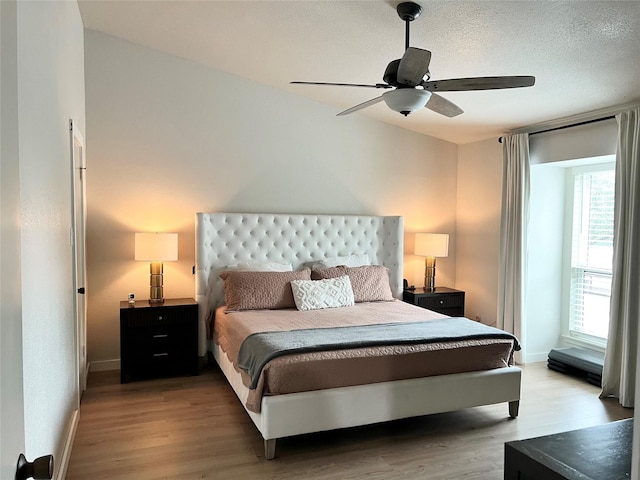 bedroom featuring a textured ceiling, light wood-type flooring, a ceiling fan, and baseboards