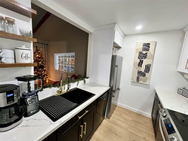 kitchen featuring washer / clothes dryer, freestanding refrigerator, white cabinets, a sink, and dark cabinets