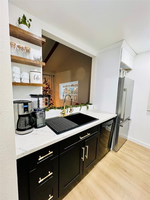 kitchen featuring dishwasher, a sink, freestanding refrigerator, and dark cabinets