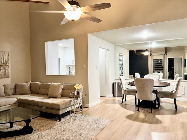 living room with a ceiling fan, baseboards, and light wood finished floors