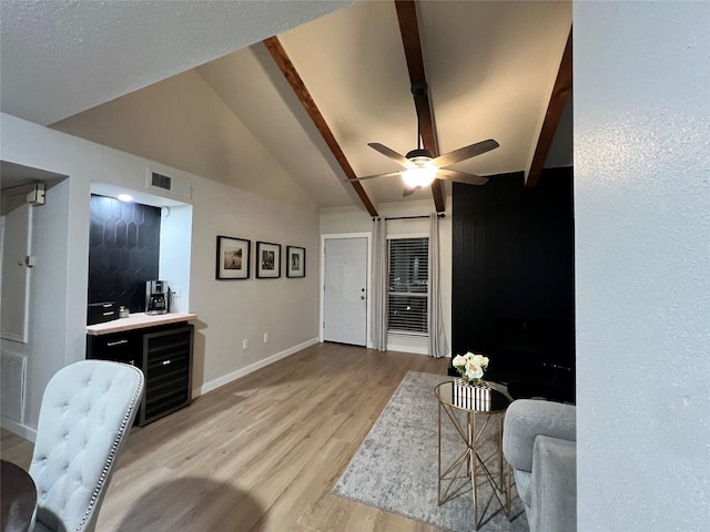 living area with visible vents, baseboards, wine cooler, vaulted ceiling with beams, and light wood-style floors