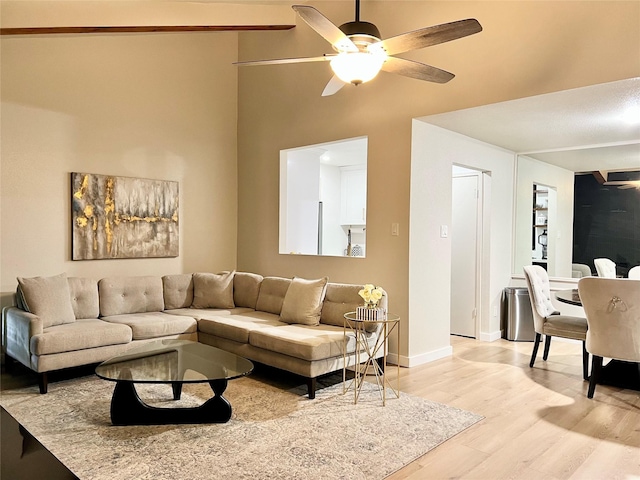 living area with baseboards, ceiling fan, and light wood-style floors