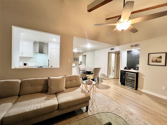 living room with light hardwood / wood-style floors, beverage cooler, beam ceiling, high vaulted ceiling, and ceiling fan