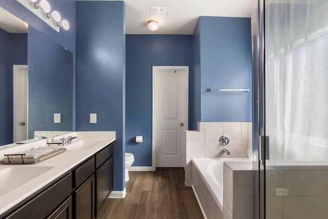 bathroom with hardwood / wood-style flooring, vanity, toilet, and a bath