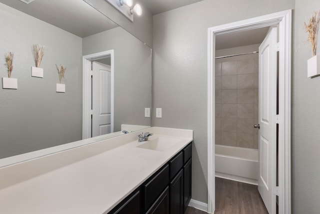 bathroom with hardwood / wood-style flooring, vanity, and tiled shower / bath