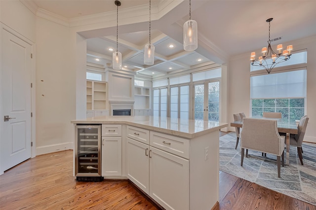 kitchen featuring white cabinetry, coffered ceiling, beverage cooler, and decorative light fixtures