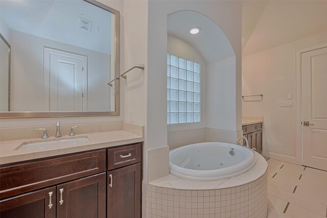 bathroom with a relaxing tiled tub, tile patterned floors, and vanity