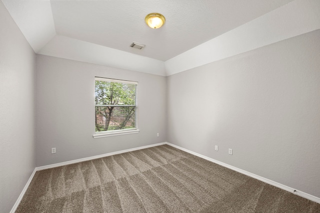 carpeted empty room with a raised ceiling and lofted ceiling