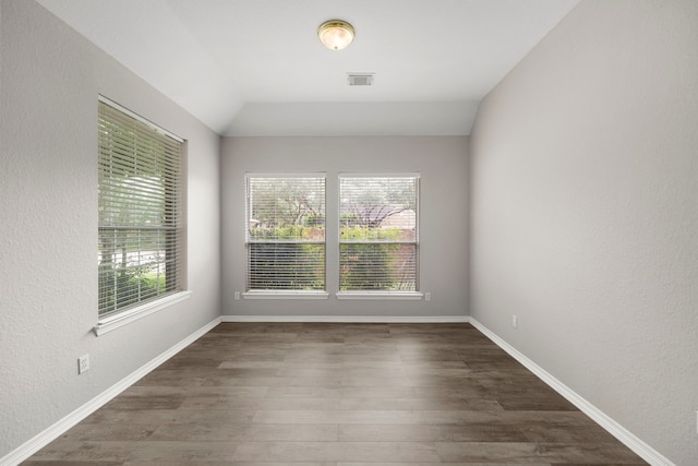 spare room with dark wood-type flooring and lofted ceiling