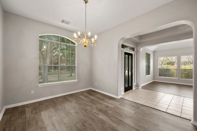 unfurnished dining area with wood-type flooring and a notable chandelier