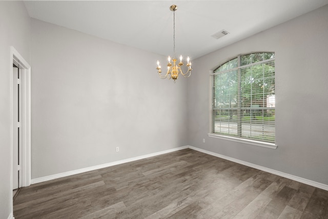 spare room featuring dark hardwood / wood-style floors and an inviting chandelier