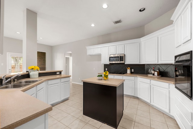 kitchen with black appliances, sink, tasteful backsplash, a kitchen island, and white cabinetry