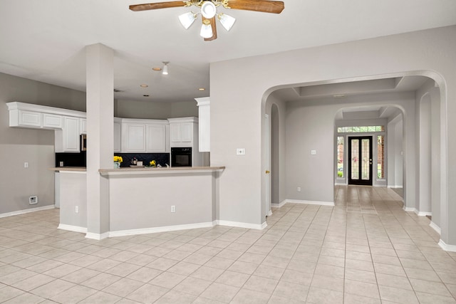 kitchen featuring kitchen peninsula, ceiling fan, white cabinets, black oven, and light tile patterned flooring