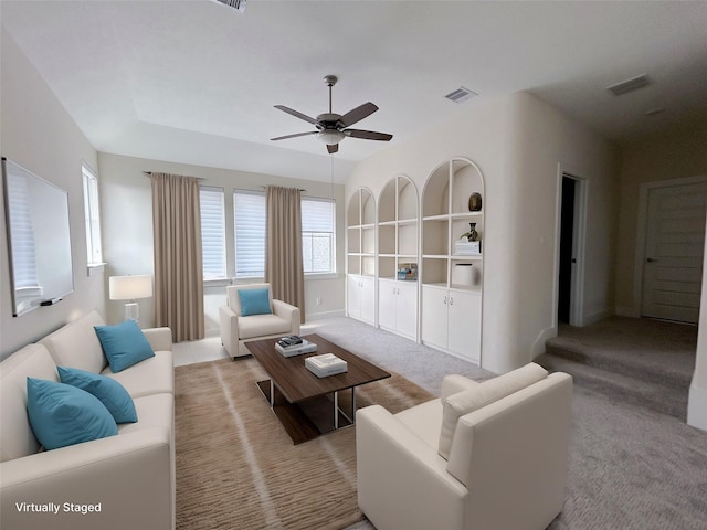 living room featuring built in shelves, ceiling fan, and light colored carpet