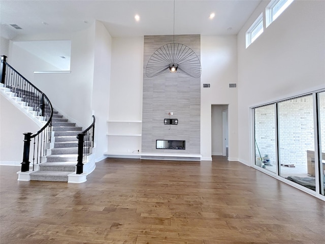 unfurnished living room with hardwood / wood-style floors, a fireplace, and a high ceiling