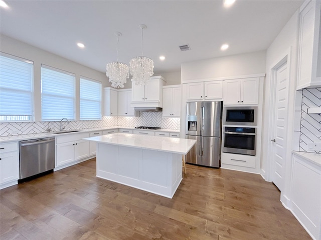 kitchen with pendant lighting, a center island, white cabinetry, and appliances with stainless steel finishes