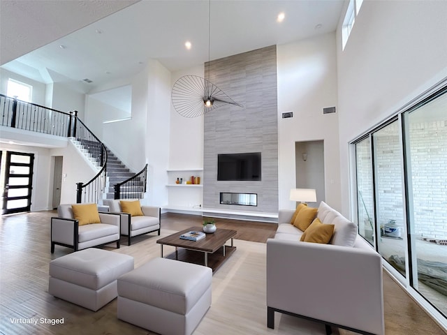 living room featuring a fireplace, a high ceiling, and light wood-type flooring