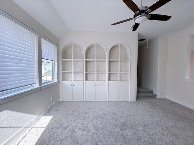 spare room featuring built in shelves, light colored carpet, and lofted ceiling